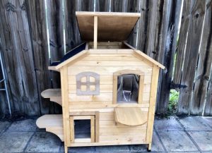 Cedar cat house with two floors, several openings and ledges, and a propped up roof